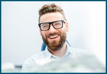 Happy man with large glass and beard smiles while visiting the dentist