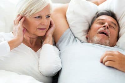 mature adult woman plugging her ears while partner snores